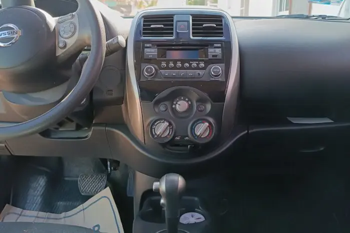 Photo of the dashboard of a car, steering wheel, pedals, Air conditionning and stereo board, automatick gear stick and glove compartment.