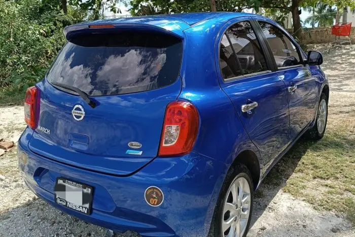 Photo of the back and right side of a blue 5 doors Nissan March Rental